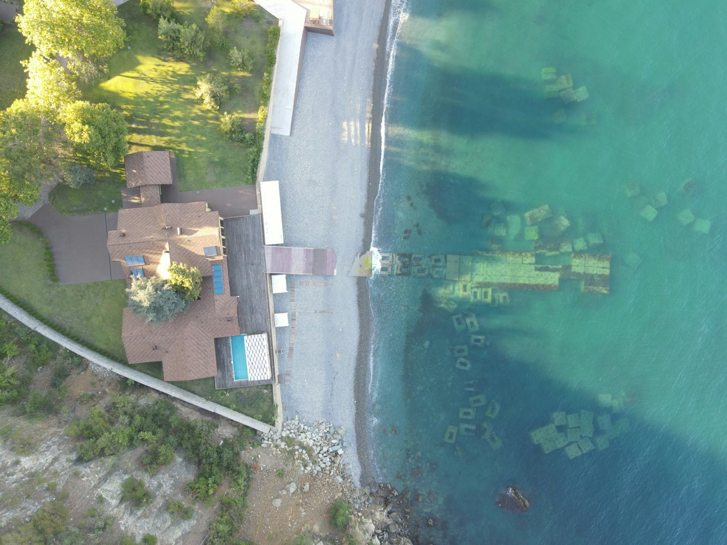 Aerial view of a waterfront house with pool and beach.