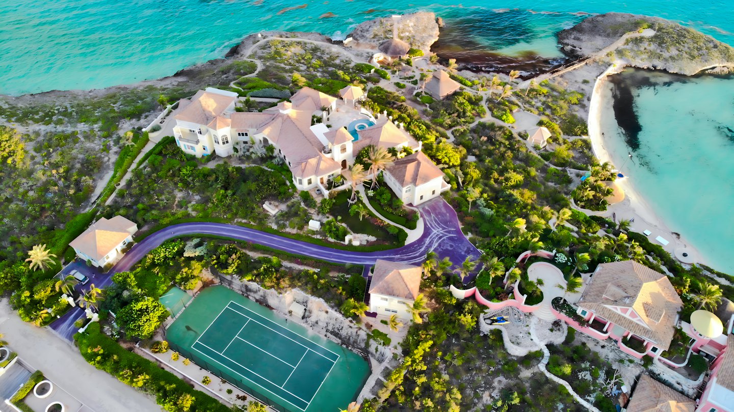 Coastal estate featuring villas, a pool, and a tennis court.